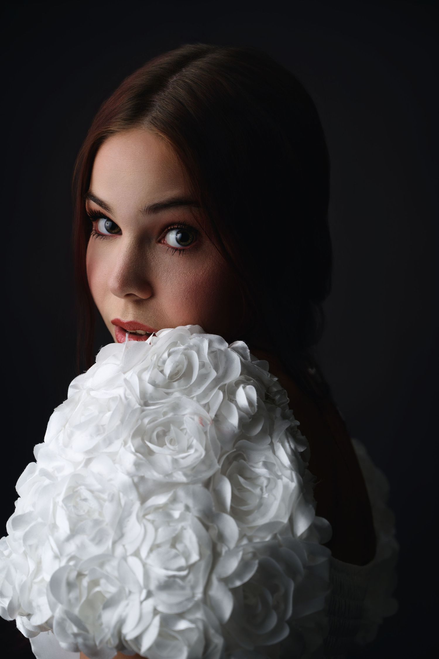 Studio portrait of a woman holding white fabric flowers
