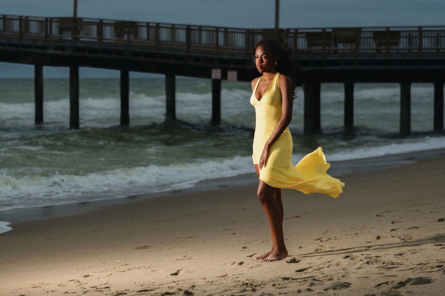 Editorial portrait of a woman in a yellow dress on the beach