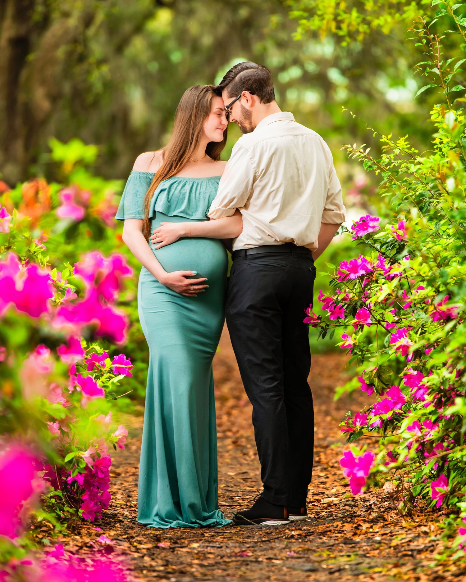 Expectant couple standing together in a flowering garden